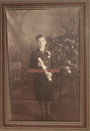Early 1900s B&W studio photo of young boy in suit, holding certificate