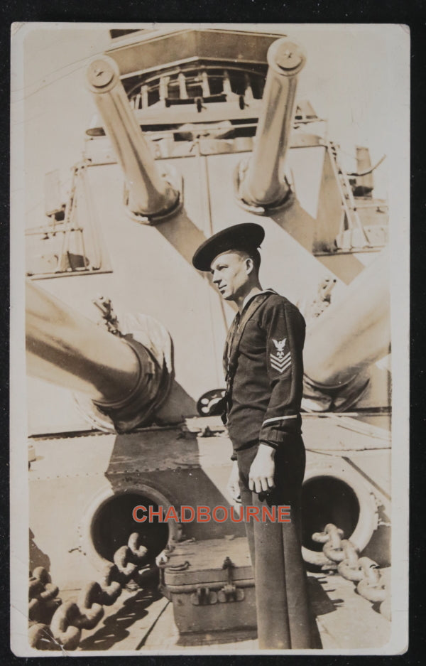 Photo postcard of US sailor in front of ship’s guns c.1919