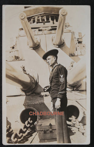 Photo postcard of US sailor in front of ship’s guns c.1919