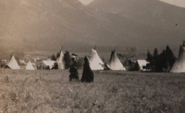 Photo postcard of First Nations encampment 1910-1930, man in headdress