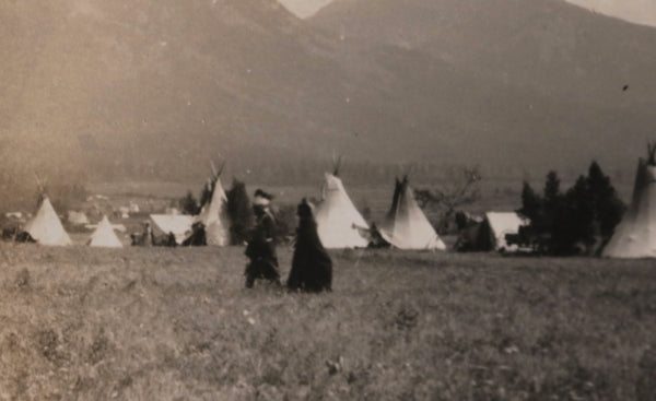 Photo postcard of First Nations encampment 1910-1930, man in headdress