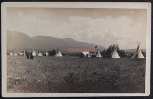 Photo postcard of First Nations encampment 1910-1930, man in headdress