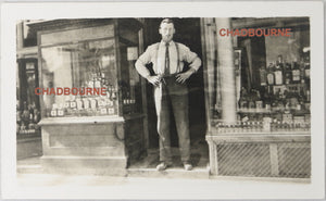 UK photo postcard of owner standing in front of liquor store c. 1910s