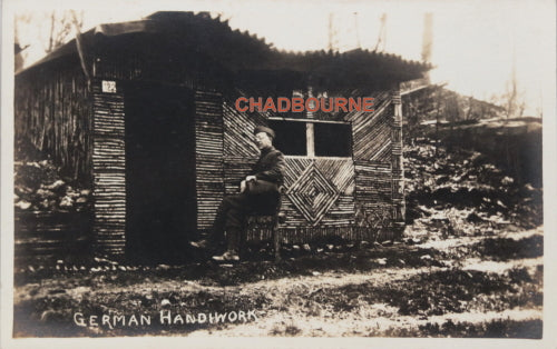 WW1 postcard photo of German soldier sitting front of homemade shelter